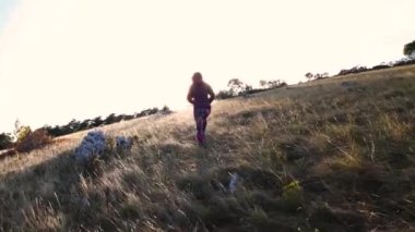 Gün batımında tarlada yürüyen bir kız.