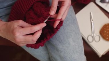 Bir kadın yün iplikten şapka örer..