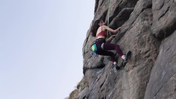 Piękna dziewczyna wspina się na skałę. — Wideo stockowe