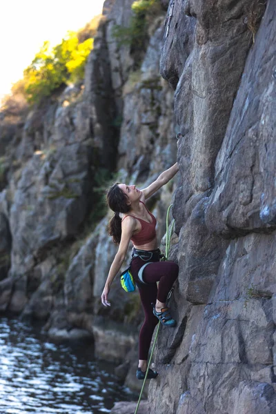 美しい少女は水の上に岩を登る 自然の中でスポーツクライミング 極端なスポーツだ フィットネスと美容 — ストック写真