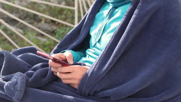 一个女人坐在阳台上，手里拿着智能手机 — 图库视频影像