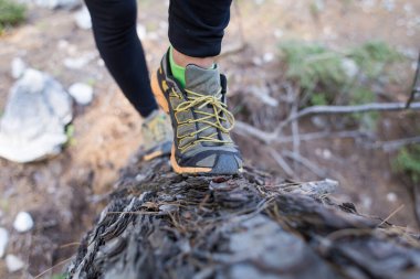 Kız engelli bir yarışa katılıyor, ormanda engelli bir yarışa katılıyor, kadın bacakları yakın planda, kadın bacakları bir kütükte koşuyor, engellerle koşuyor.