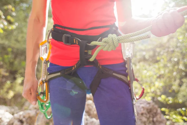 女の子のロッククライマーは山の中で安全な登山のためのハーネスにロープで自分自身を結びつけます スポーツの安全よ ロッククライミングの準備だ 路上でスポーツをしています — ストック写真