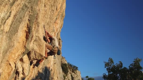 Un hombre fuerte trepa una roca — Vídeos de Stock