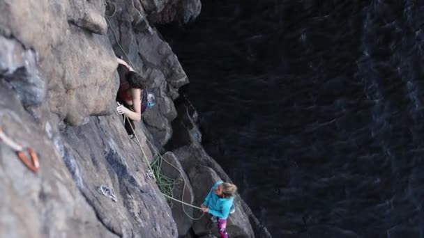 Dziewczyna wspina się na skałę nad wodą — Wideo stockowe