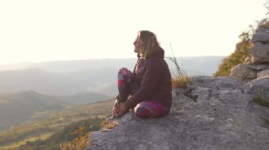 Kız uçurumun kenarında oturur ve uzaklığa bakar.. 