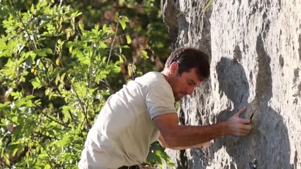 En stærk mand klatrer op ad en klippe – Stock-video