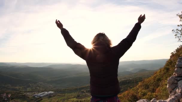 Jong meisje stak haar handen op naar de zon tegen de achtergrond van de bergen, slow motion — Stockvideo