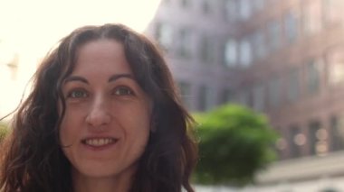 Uzun kıvırcık saçlı, gülümseyen bir kadın. 