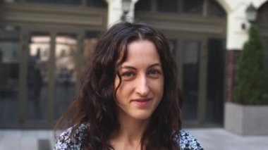 Uzun kıvırcık saçlı, gülümseyen bir kadın. 