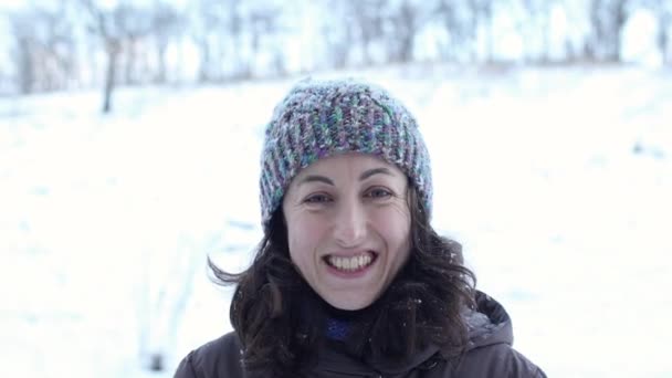 Μια χαμογελαστή γυναίκα κοιτάζει τις νιφάδες χιονιού που πέφτουν — Αρχείο Βίντεο