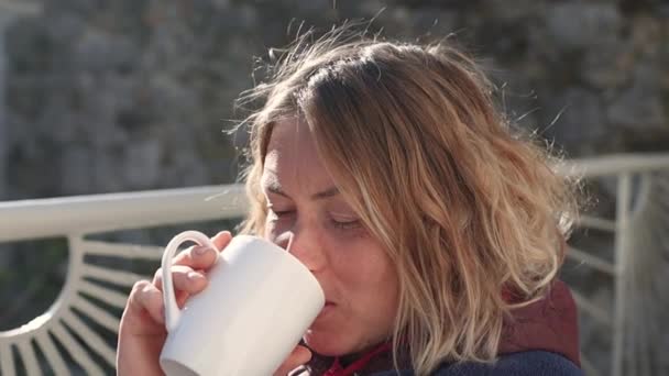 Woman drinks a hot drink from a mug — Wideo stockowe