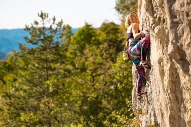 Kız kayaya tırmandı. Dağcı doğal arazide antrenman yapar. Olağanüstü bir spor. Açık hava aktiviteleri. Hırvatistan 'ın Kompan bölgesinde zorlu bir kaya tırmanışının üstesinden gelen bir kadın görülüyor