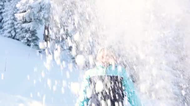 Μια γυναίκα ρίχνει χιόνι στο φόντο του χιονιού καλυμμένο έλατα — Αρχείο Βίντεο