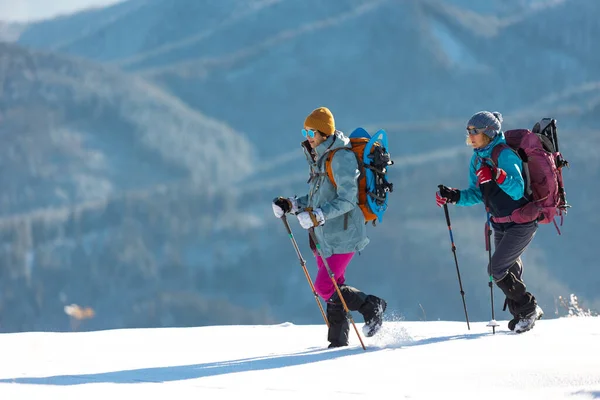 两名妇女穿着雪鞋在雪地里行走 冬季徒步旅行 两名男子穿着登山装备在山上行走 — 图库照片