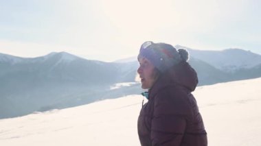 Bir kadın karla kaplı köknar ağacının zeminine kar atıyor.