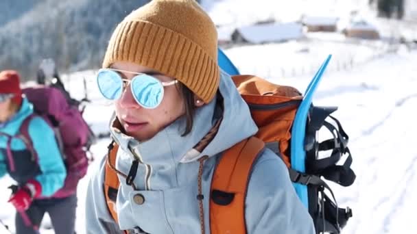 Két nő hótalppal a hátizsákján sétál télen. — Stock videók