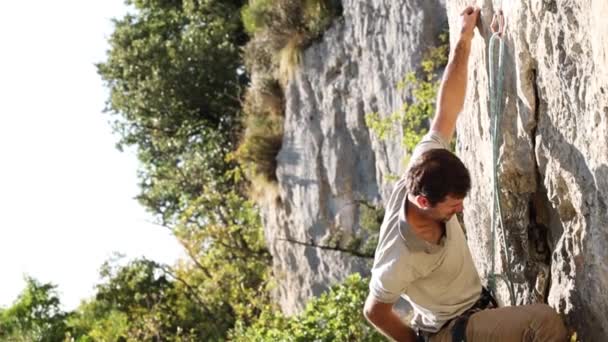 Egy erős ember felmászik egy sziklára. — Stock videók
