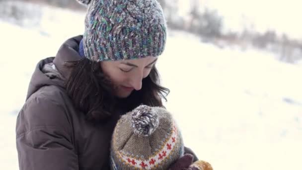 冬の散歩中に女性が子供を抱きかかえて — ストック動画