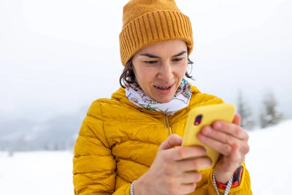 Kobieta Żółtej Kurtce Trzyma Żółty Smartfon Rękach Dziewczyna Robi Selfie — Zdjęcie stockowe
