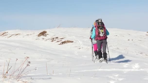 Дві жінки з рюкзаками ходять в зимових походах — стокове відео