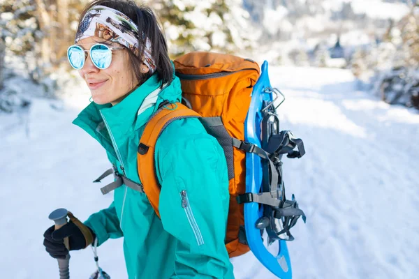 一个女人背着雪鞋走路 冬天徒步旅行 冬天爬山 带着远足装备 — 图库照片