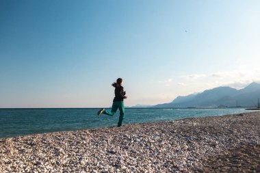 Sabah koşusu yapan bir kız, deniz kıyısında spor yapmak için koşan bir kadın, kumsalda koşan bir atlet.