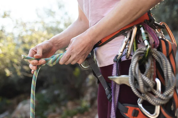 ロッククライマーは登山のための機器を準備し 女性は彼女の手にロープを保持し 登山者は結び目を結びます — ストック写真