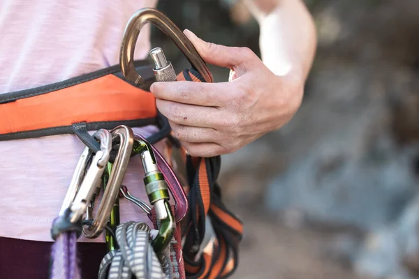 ロッククライマーは登山のための装備を準備し 女性はロープとキャビネアを手に持ち キャビネアを手に入れ クライマーのハーネスをすばやく描きます — ストック写真