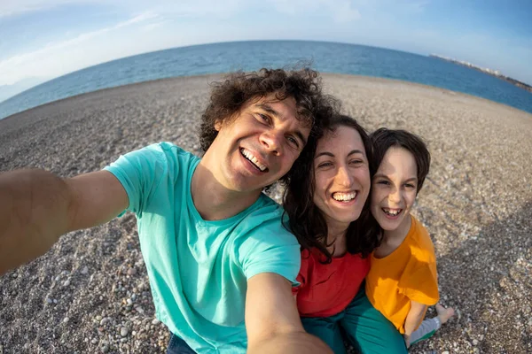 Aile deniz kıyısında selfie çekiyor, ailesiyle plajda dinlenen bir çocuk, mutlu bir aile, bir erkek ve bir kadın fotoğraf çekiyor.