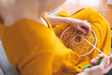 Kadın ipliklerden, ev dekorasyonundan, el yapımı tılsımlardan rüya yakalayıcı yapıyor.