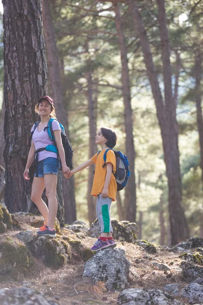 Bir kadın oğluyla ormanda yürür, annesiyle yürüyüşe çıkar, sırt çantalı bir çocuk parka gider, çocuklarla seyahat eder, çocuk annesinin elini tutar, dağ yolu, Anneler Günü..