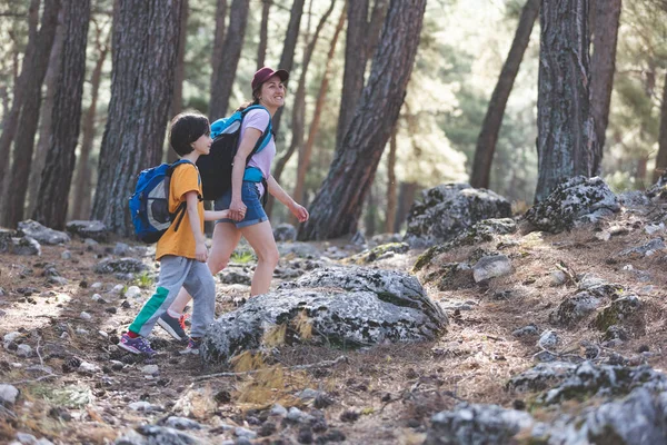 Bir kadın oğluyla ormanda yürür, annesiyle yürüyüşe çıkar, sırt çantalı bir çocuk parka gider, çocuklarla seyahat eder, çocuk annesinin elini tutar, dağ yolu, Anneler Günü..
