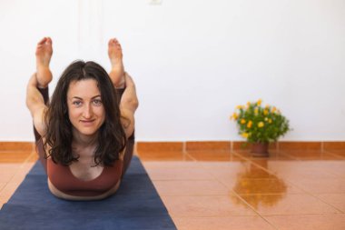 Kadın evde yoga yapıyor, zayıf kız egzersiz yapıyor, esneme egzersizleri yapıyor.