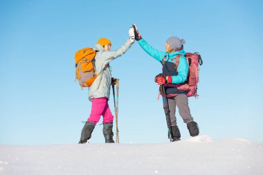 İki kadın karda kar ayakkabılarıyla yürüyor, kış yürüyüşü yapıyor, kışın dağlarda iki kişi yürüyüş ekipmanları, beşlik çakıyor.