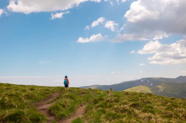Bir çocukla dağlarda yürümek, sırt çantalı bir çocuk dağ yolunda yürümek, çocuklar için açık hava eğlencesi..