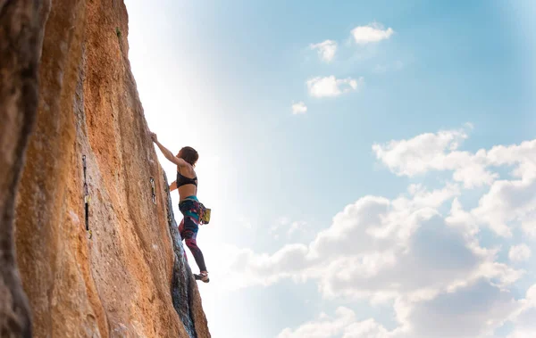 女性は青い空に対して岩を登る 強い女の子は強さと持久力を訓練 極端なスポーツ 自然の地形にロッククライミング ロッククライマーはロープで登る — ストック写真