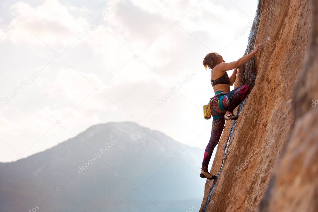 A woman climbs a rock, a strong girl trains strength and endurance, extreme sport, rock climbing on natural terrain, a rock climber climbs with a rope