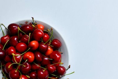 Beyaz bir masada bir kase tatlı kiraz, tatlı çilek, yaz hasadı