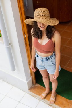 Hasır şapkalı bir kadının portresi, ahşap bir evin eşiğinde gülümseyen bir kız.