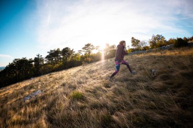 Kız gün batımında çayırda yürüyor. Doğa yürüyüşü.