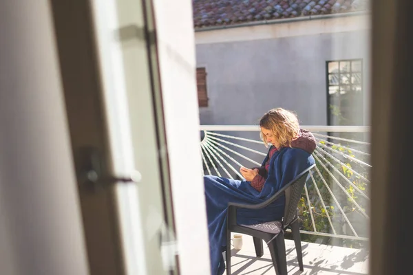 Девушка Телефоном Сидит Солнечном Балконе Покрытом Одеялом — стоковое фото