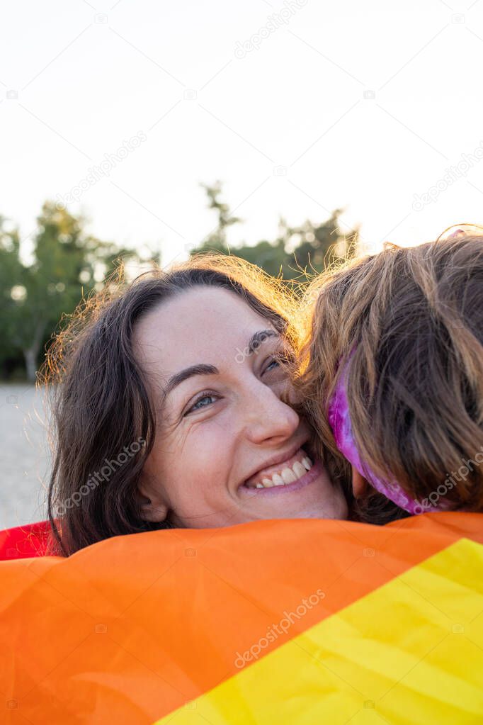 young lesbian couple hugs tenderly. rainbow flag on the street. equal rights for the lgbt community, intimacy and feelings for two girl