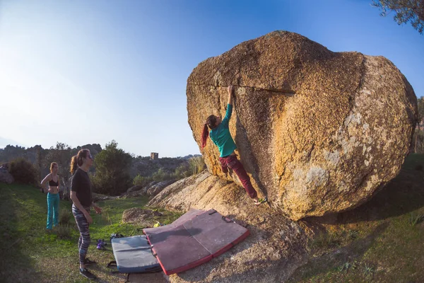 Friends go in for sports in nature, bouldering on rocks, girl climbs a big stone, woman is belayng partner, outdoor recreation, bouldering on the