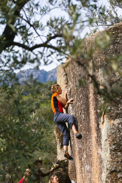 A strong girl climbs a large boulder, bouldering on natural terrain, friends are climbing in Turkey, a large boulder in the park, friends support, gymnastic belaying