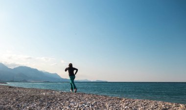 Sabah koşusu yapan bir kız, deniz kıyısında spor yapmak için koşan bir kadın, kumsalda koşan bir atlet.