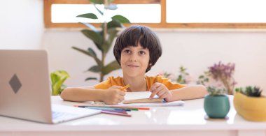 Çocuk uzaklık dersi sırasında dizüstü bilgisayar kullanıyor. Çocuk internetten iletişim kuruyor..