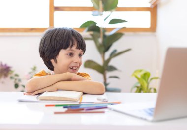 Online distance learning. a boy with a computer communicate via videoconference with a teacher and a class group. The child communicates online.