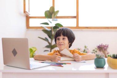 Online distance learning. a boy with a computer communicate via videoconference with a teacher and a class group. The child communicates online.