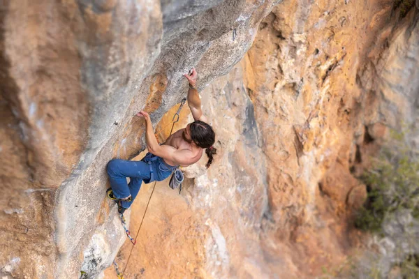 Rock climber climbs to the top of the cliff, strong man climbs the cliff, strength and endurance training